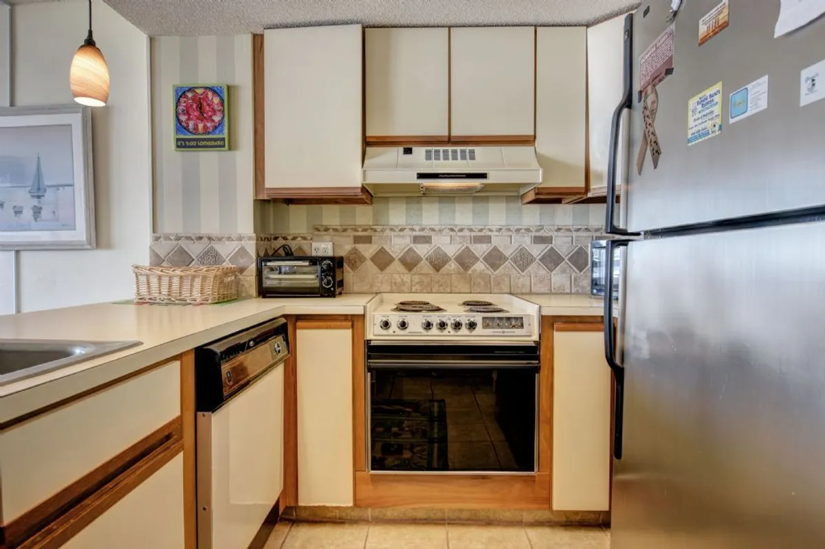 A warm, homey kitchen scene featuring a modern stove, refrigerator, and spacious sink area. The countertops are uncluttered, and the overall design encourages culinary creativity and gathering. The space feels practical yet inviting, enabling group cooking and easy clean-up.